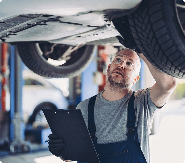 Auto technician examining car underside