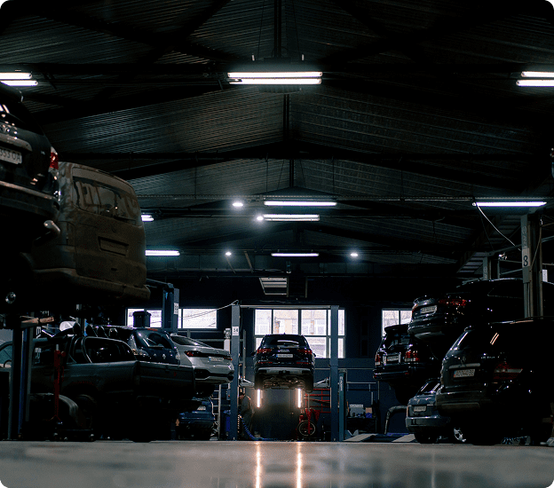 Cars on lifts in dimly lit garage.