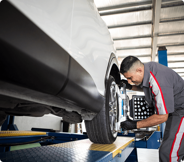 Technician adjusting vehicle tire alignment